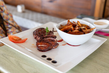 Gourmet Duck Breast with French Fries Served on a White Plate