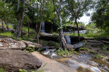 Clear stream waterfall in Phu Pha Yon National Park, a small serene cascade surrounded by lush tropical forest in Thailand.