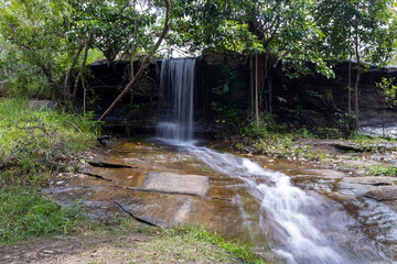 A peaceful view of Than Nam Sai waterfall, a small clear stream in Phu Pha Yon National Park, Thailand. Surrounded by green trees, perfect for nature, travel, and landscape concepts.
