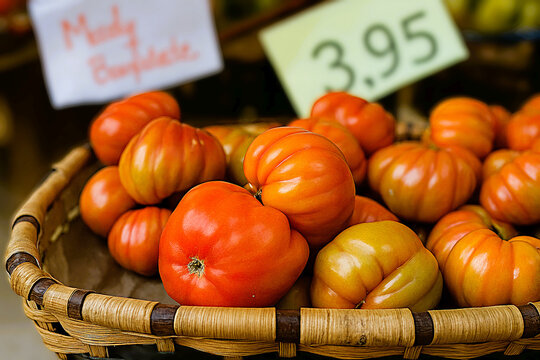 Close up photograph of tomatoes displayed at a grocery store on an oak basket.