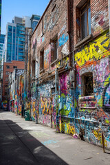 Fototapeta premium A graffiti-covered wall in an urban alley with overlapping paint tags, murals, and colorful artistic layers.