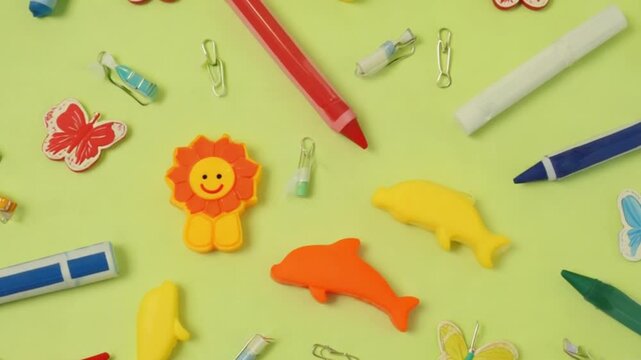 Colorful assortment of playful stationery items and erasers on a vibrant green background