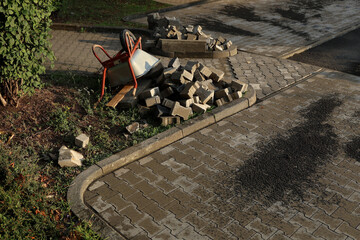 Workers are installing paving stones in a garden pathway, arranging the stones with precision under...
