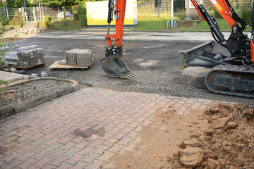 Workers are installing paving stones in a garden pathway, arranging the stones with precision under clear skies.