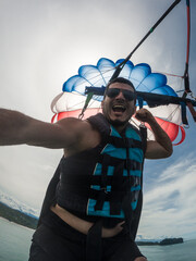 A vertical shot of a happy and euphoric adult man parasailing over the beaches of Manuel Antonio,...