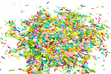 Pile of colorful sprinkles on a white background. The sprinkles are in various colors and sizes, creating a vibrant and playful atmosphere
