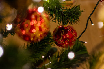 Red and gold ornament hangs from a Christmas tree. The ornament is shaped like a ball and has a...
