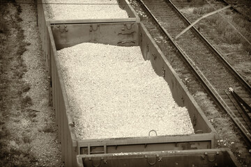 A train with open carriages transports titanium ore from a mining site to a loading port for...