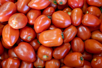Many ripe red tomatoes. Cherry tomatoes. Pink tomatoes. Tomatoes in a box. Sale of tomatoes at the market and store. Background. Top view. Concentration sale at the market and store. Farm products. 