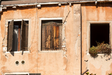 Old building with weathered plaster walls and wooden window shutters in Venice