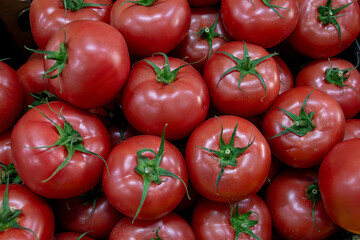 Many ripe red tomatoes. Cherry tomatoes. Pink tomatoes. Tomatoes in a box. Sale of tomatoes at the market and store. Background. Top view. Concentration sale at the market and store. Farm products. 