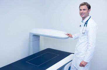 Bone densitometer waiting beside dark scanning table marked white in medical exam room, copy space