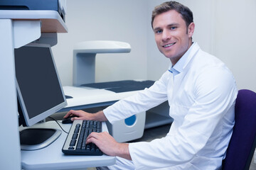 Flat-panel medical imaging scanner operating beside mouse on desk under bright clinical lighting