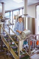 Stainless steel keg resting on grated stairway inside brewery production area, with polished tanks