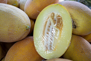 Melons ripe, one cut in half. Many ripe melons as a background, top view. Melon trade at the market.