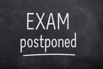 Obraz premium Exam postponed notice written on chalkboard, school cancellation update, test reschedule announcement, education disruption message, blackboard with delay sign, academic planning, student calendar ale