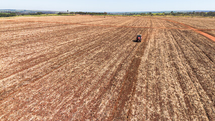 Tractor working on dry farmland during sunny day in Barretos, São Paulo, Brazil