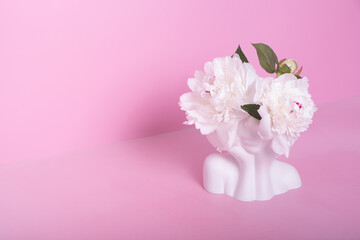 Creative plaster vase in the shape of a head with white peony flowers. Mind care concept