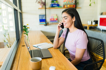 Smiling freelancer working remotely in cafe and talking on phone