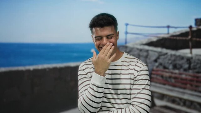 Young man smiling at seaside promenade with ocean background on a sunny day