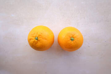 Dos naranjas enteras sobre fondo claro, fotografiadas en cenital. Imagen minimalista y natural que destaca los colores vivos y la textura de la fruta fresca.