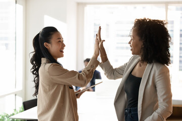 Collaboration and unity. Excited positive young professionals multiethnic female coworkers give...