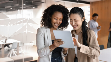 Professional service using gadget. Friendly young female bank manager insurance agent financial advisor consult assist happy smiling woman client signing digital agreement on tablet screen. Copy space