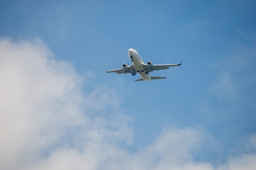 Obraz premium Avión volando en un cielo azul con nubes blancas mientras se aproxima a Puerto Rico. La imagen captura el momento de llegada a la isla caribeña, simbolizando viajes, turismo y transporte aéreo.