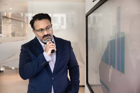 Data driven analysis. Thoughtful mature businessman corporate ceo financial analyst project leader look at screen with statistic graphs in boardroom contemplate market forecast ponder investment risks