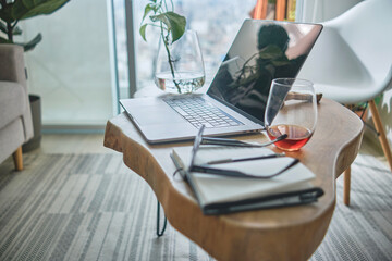 Modern home office setup featuring laptop, plants, and notebook on a wooden table, ideal for remote...