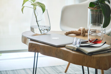 Modern home office setup featuring laptop, plants, and notebook on a wooden table, ideal for remote...