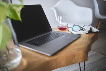 Modern home office setup featuring laptop, plants, and notebook on a wooden table, ideal for remote...