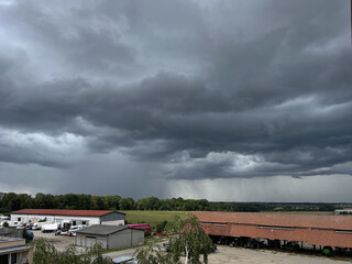 Storm clouds over the landscape. View of an agricultural environment with garages and fields.