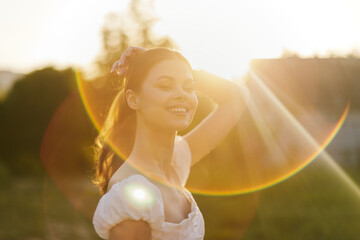 Smiling young woman in a white dress enjoying a sunny day outdoors, radiating positivity and joy...
