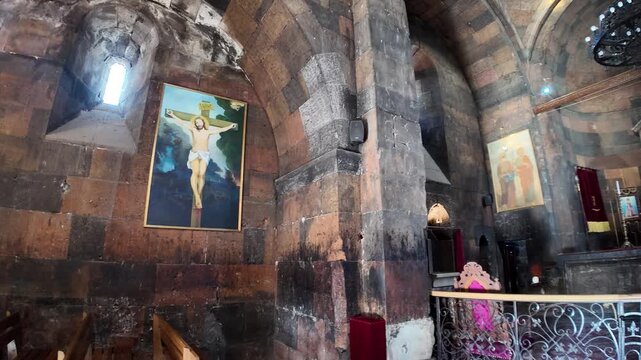 Sunlight through a small window highlights paintings of Jesus Christ on the cross and other religious figures in Church of the Holy Mother of God, within Khor Virap an Armenian monastery in Armenia