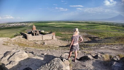 Blonde haired female tourist in front of Mount Ararat with Khor Virap monastery in the Ararat plain in Armenia