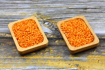 Red lentils in wooden bowl on wooden table background. Top view, copy space. Flat lay.