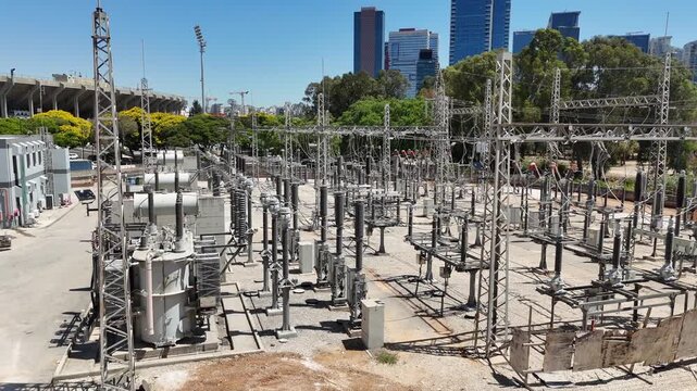 Aerial drone view of an industrial electrical substation with transformers and high-voltage power lines. Infrastructure of the national power grid, captured from above.

