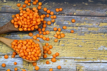 Red lentils in wooden bowl on wooden table background. Top view, copy space. Flat lay.