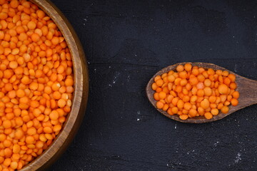 Red lentils in wooden bowl on wooden table background. Top view, copy space. Flat lay.