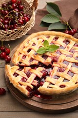 Tasty cut cherry pie and berries on wooden table, closeup