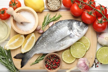 Naklejka na ściany i meble Fresh raw dourade with spices on white wooden table, flat lay. Fish and seafood delicacies