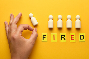 Dismissal. Word Fired and woman throwing human figure away on yellow background, top view