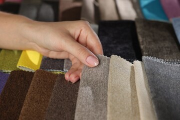 Woman choosing fabric among different samples indoors, closeup