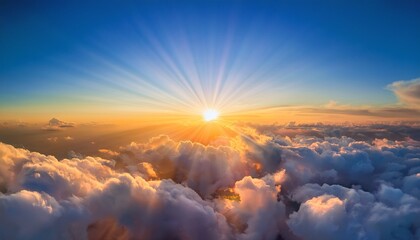 sunrise with vibrant orange and yellow rays radiating from horizon surrounded by fluffy clouds against clear blue sky creating warm and uplifting atmosphere