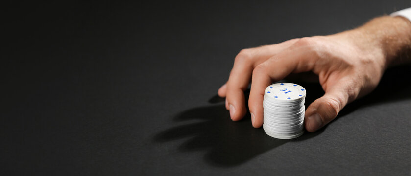 Male hand with chips for gambling games on dark background