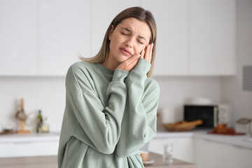 Young woman suffering from tooth ache at home