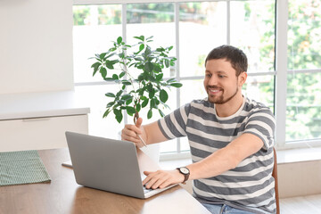 Young male teacher with laptop giving online lesson at home