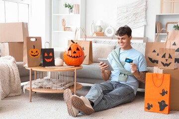 Young man with credit card and tablet computer shopping online for Halloween at home