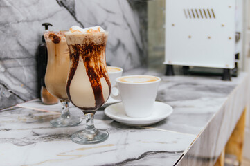 Two glasses of chocolate milk with whipped cream on a marble counter